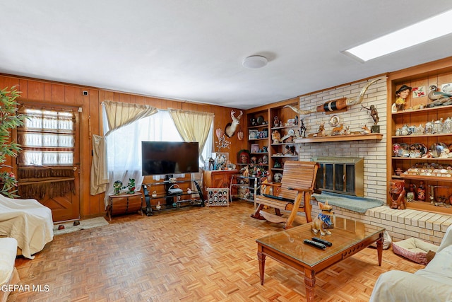 living room with built in shelves, wooden walls, and a fireplace