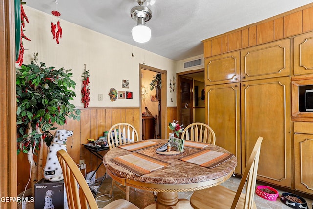 dining room with wood walls, wainscoting, and visible vents