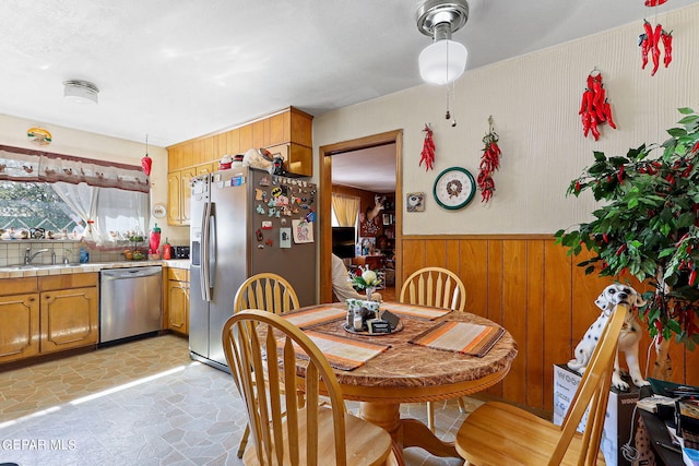 dining space with stone finish flooring, wooden walls, and wainscoting