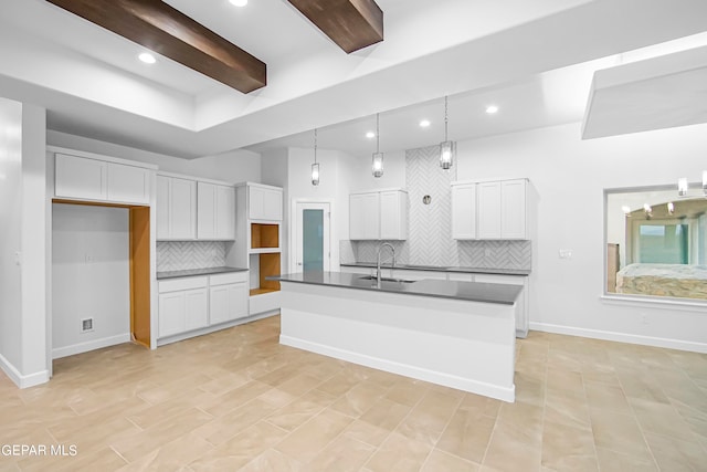 kitchen with white cabinets, pendant lighting, sink, a center island with sink, and decorative backsplash