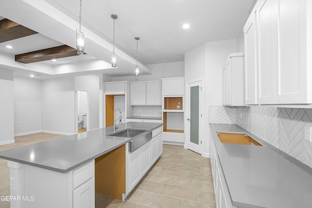 kitchen with white cabinets, beamed ceiling, sink, a center island with sink, and decorative backsplash