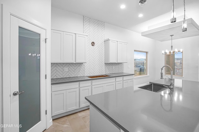 kitchen with hanging light fixtures, decorative backsplash, light tile patterned floors, sink, and a chandelier