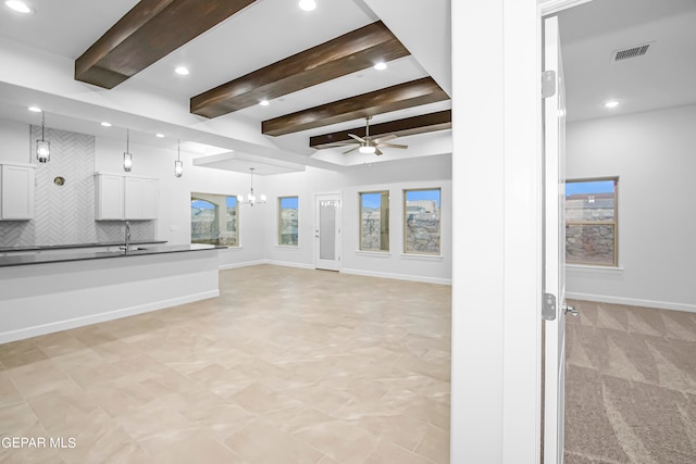 unfurnished living room featuring sink, ceiling fan with notable chandelier, and beam ceiling