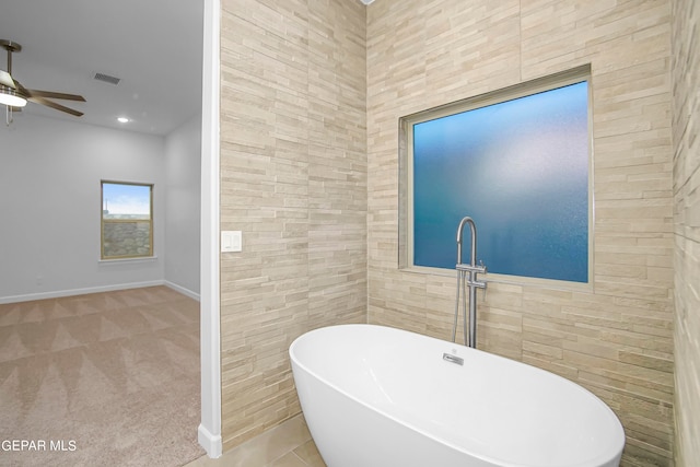 bathroom with tile walls, a tub to relax in, and ceiling fan