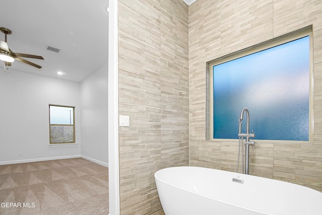 bathroom with tile walls, a washtub, and ceiling fan