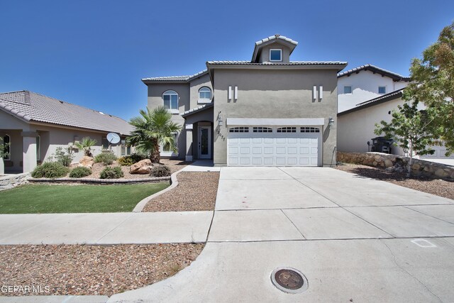 mediterranean / spanish house with driveway, an attached garage, a tile roof, and stucco siding