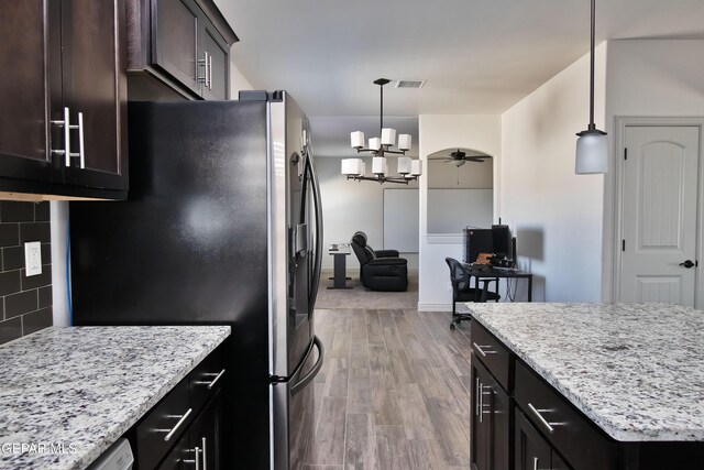 kitchen featuring tasteful backsplash, stainless steel fridge, hanging light fixtures, and wood finished floors