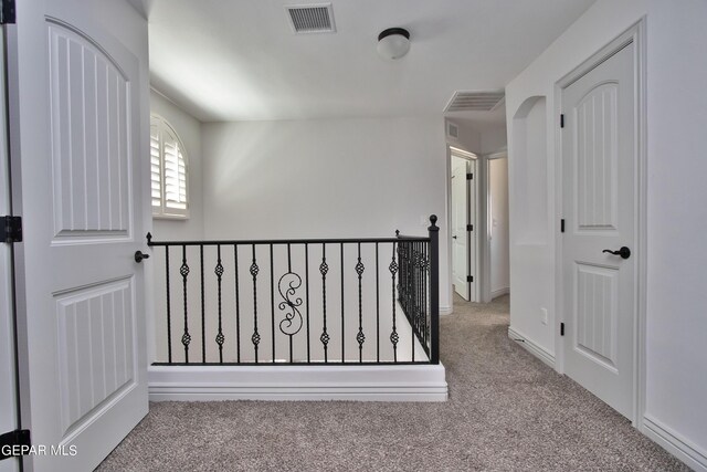 hall with visible vents and light colored carpet