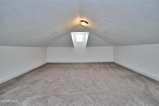 bonus room featuring a textured ceiling, carpet floors, vaulted ceiling, and visible vents