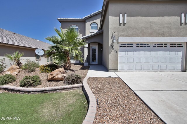 view of front facade featuring a garage, driveway, a tiled roof, and stucco siding