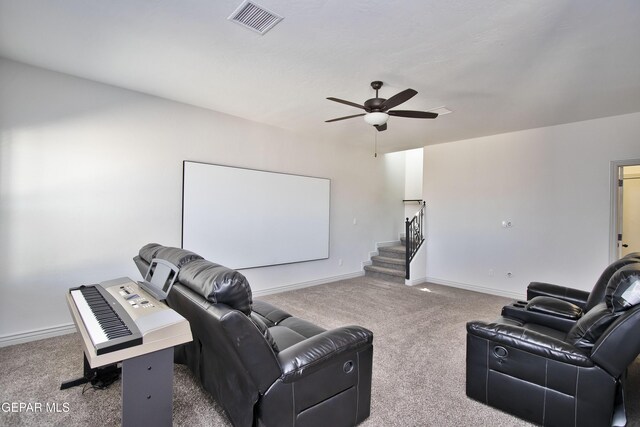 carpeted home theater room with a ceiling fan, visible vents, and baseboards