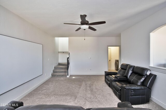 living room with light colored carpet, a ceiling fan, baseboards, stairway, and washer / clothes dryer