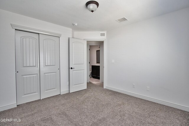 unfurnished bedroom with carpet floors, a closet, visible vents, and baseboards