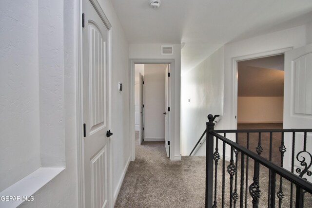 corridor with light carpet, baseboards, visible vents, and an upstairs landing