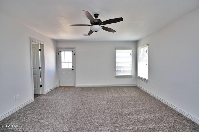 carpeted spare room featuring visible vents, ceiling fan, and baseboards