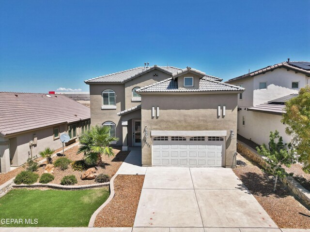 mediterranean / spanish house featuring a garage, a tile roof, concrete driveway, and stucco siding