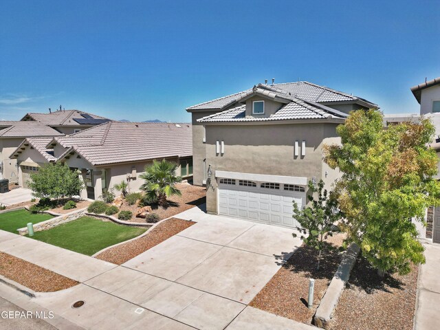 view of front of house featuring a tile roof, driveway, an attached garage, and stucco siding