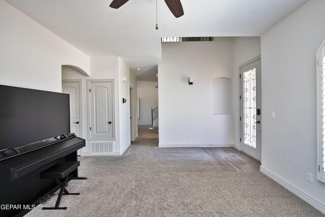 interior space featuring light carpet, baseboards, and arched walkways