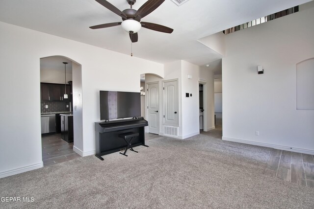 living area featuring carpet, arched walkways, visible vents, a ceiling fan, and baseboards