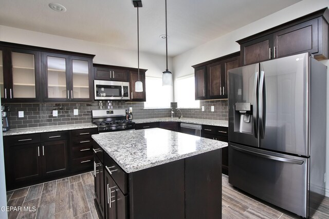 kitchen with dark brown cabinetry, stainless steel appliances, a center island, glass insert cabinets, and pendant lighting