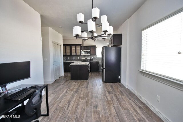 kitchen with decorative light fixtures, tasteful backsplash, appliances with stainless steel finishes, glass insert cabinets, and a kitchen island