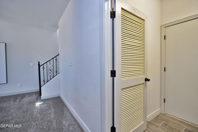 stairs with carpet floors, baseboards, and wood finished floors