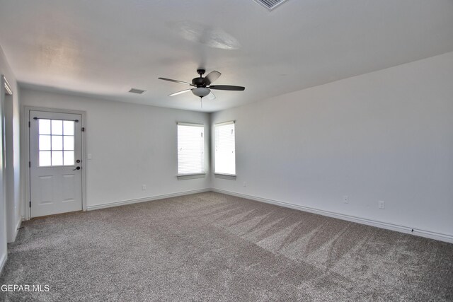 spare room featuring ceiling fan, a wealth of natural light, carpet, and visible vents