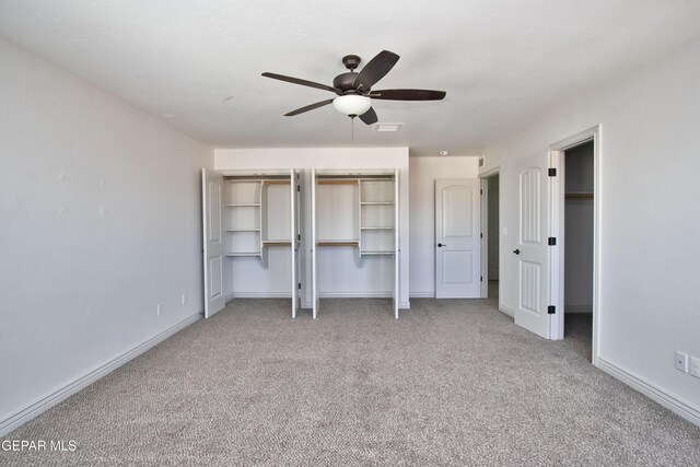 unfurnished bedroom featuring multiple closets, visible vents, a ceiling fan, light carpet, and baseboards