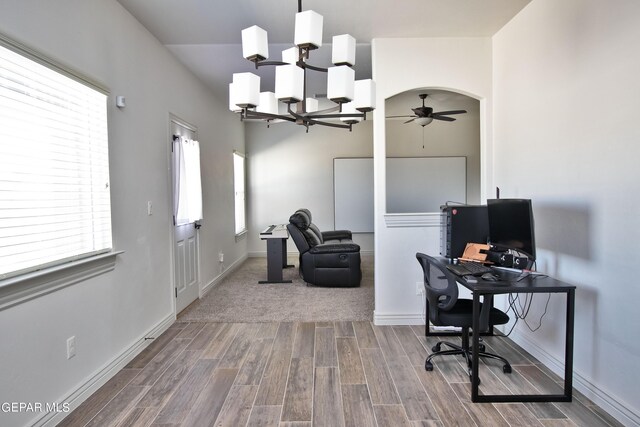 office space with ceiling fan with notable chandelier, arched walkways, baseboards, and wood finished floors