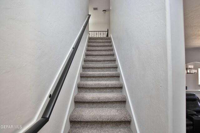 stairs with a textured wall and baseboards