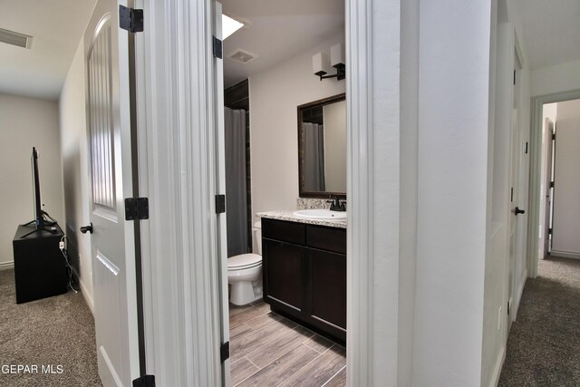 bathroom featuring toilet, wood finished floors, vanity, and visible vents