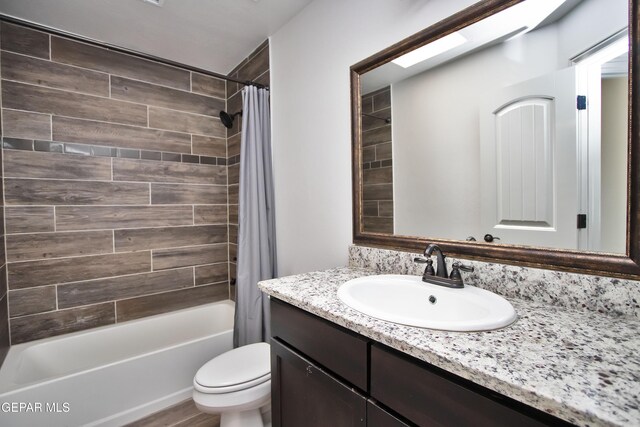 bathroom featuring toilet, shower / tub combo with curtain, and vanity