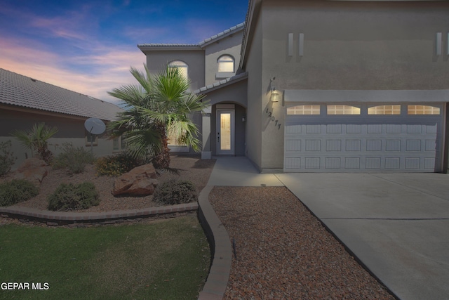 mediterranean / spanish home with driveway, a tile roof, a garage, and stucco siding