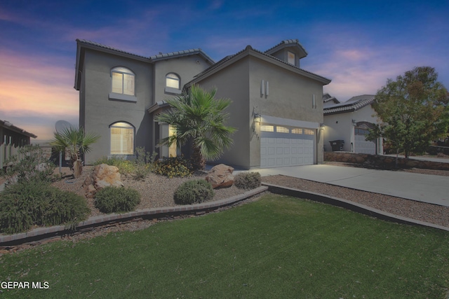 mediterranean / spanish home with driveway, an attached garage, a lawn, and stucco siding