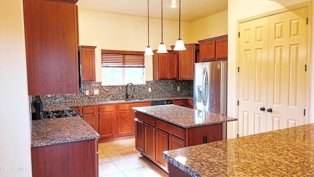 kitchen with backsplash, sink, a center island, stainless steel fridge, and hanging light fixtures