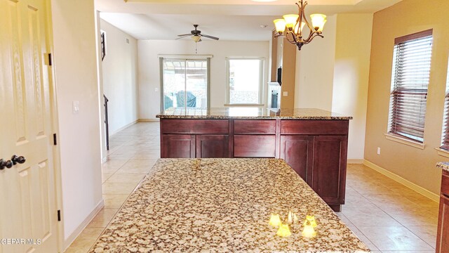 kitchen featuring ceiling fan with notable chandelier, a center island, and light tile patterned flooring