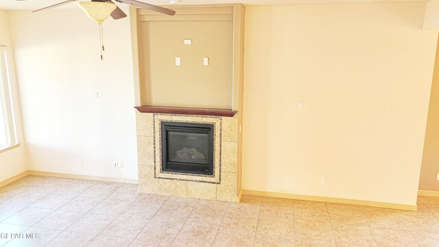 unfurnished living room with ceiling fan, a tiled fireplace, and tile patterned floors