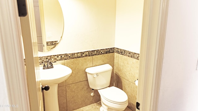 bathroom with backsplash, sink, tile patterned floors, tile walls, and toilet