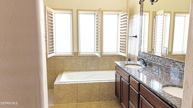 bathroom featuring plenty of natural light, tiled tub, vanity, and tile patterned floors