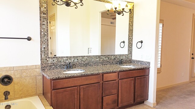 bathroom featuring a notable chandelier, a bathing tub, and vanity