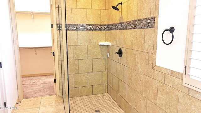 bathroom with tile patterned flooring and a tile shower