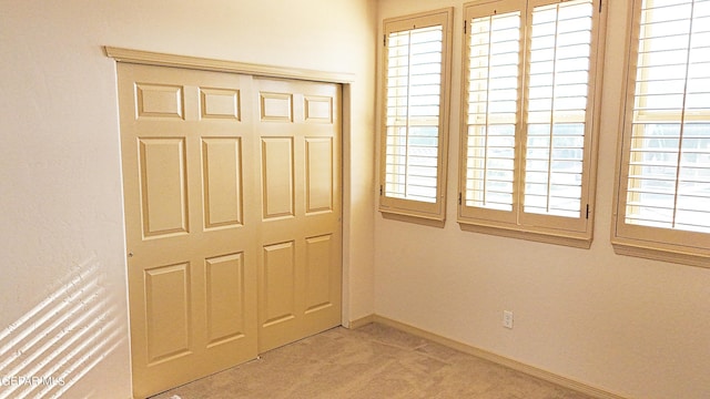 unfurnished bedroom with carpet floors, multiple windows, and a closet