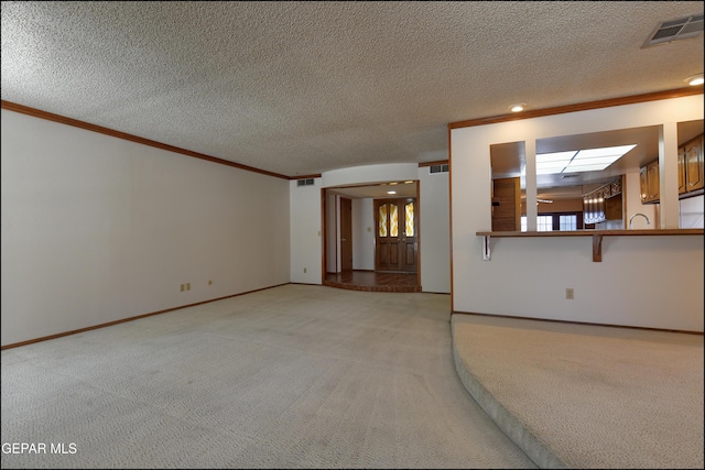 unfurnished living room featuring a textured ceiling, ornamental molding, visible vents, and light colored carpet