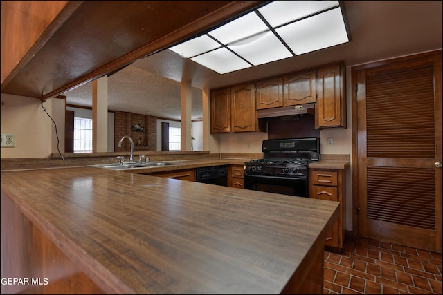 kitchen with brown cabinets, a peninsula, under cabinet range hood, black appliances, and a sink