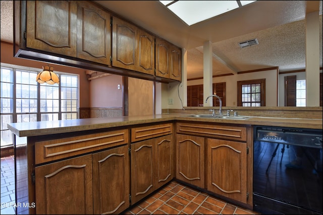 kitchen with black dishwasher, visible vents, brown cabinets, a peninsula, and a sink