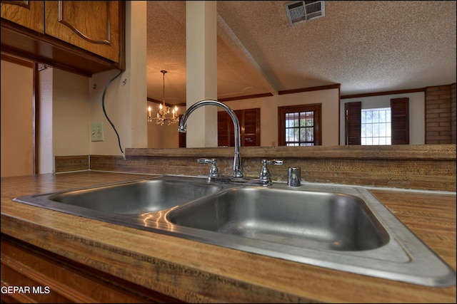 details featuring visible vents, brown cabinetry, a notable chandelier, a textured ceiling, and a sink