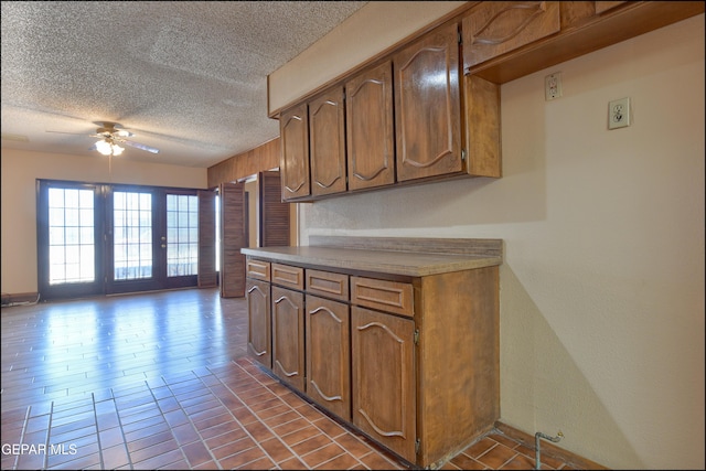 kitchen featuring light countertops, brown cabinets, ceiling fan, and a textured ceiling