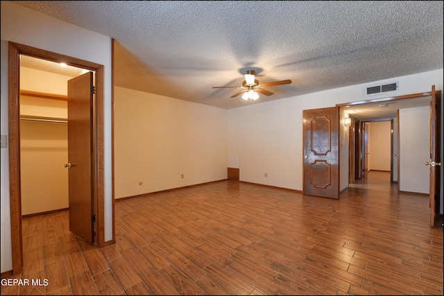 unfurnished bedroom featuring a textured ceiling, wood finished floors, visible vents, and baseboards