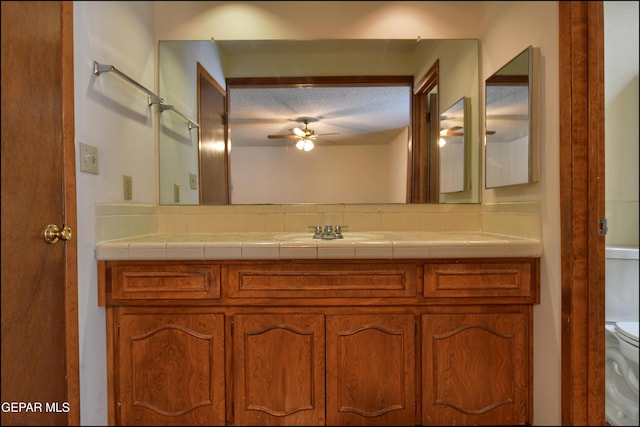 bathroom featuring a textured ceiling, vanity, toilet, and a ceiling fan