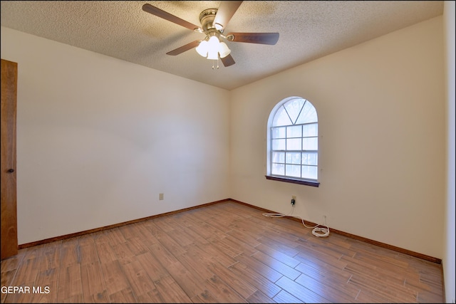 spare room featuring baseboards, light wood-style flooring, and a textured ceiling